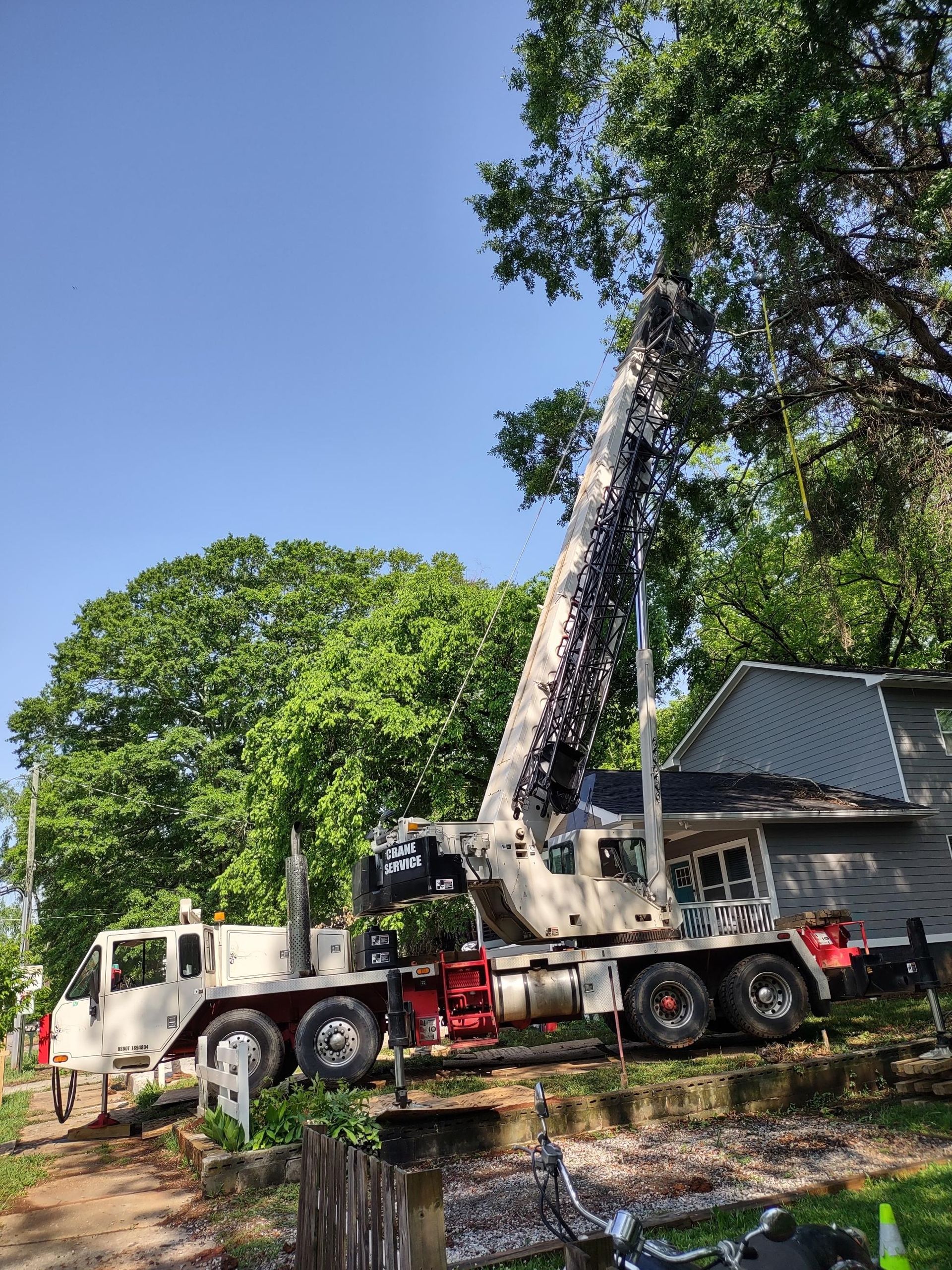 A large truck with a crane attached to it is parked in front of a house.