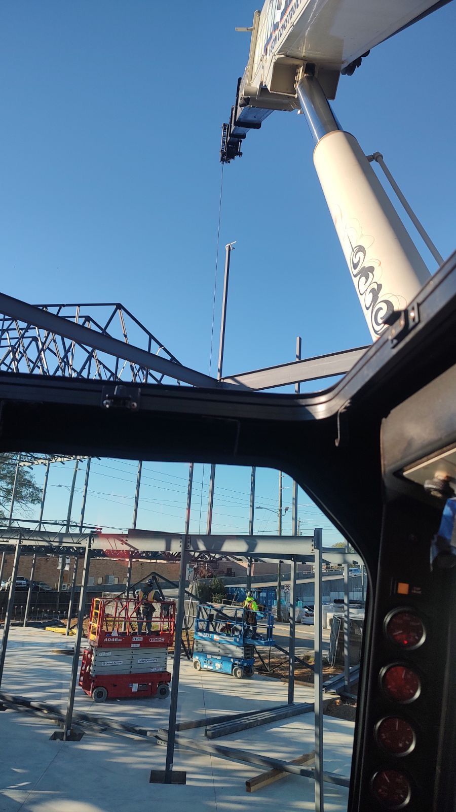 A crane is lifting a metal structure at a construction site.