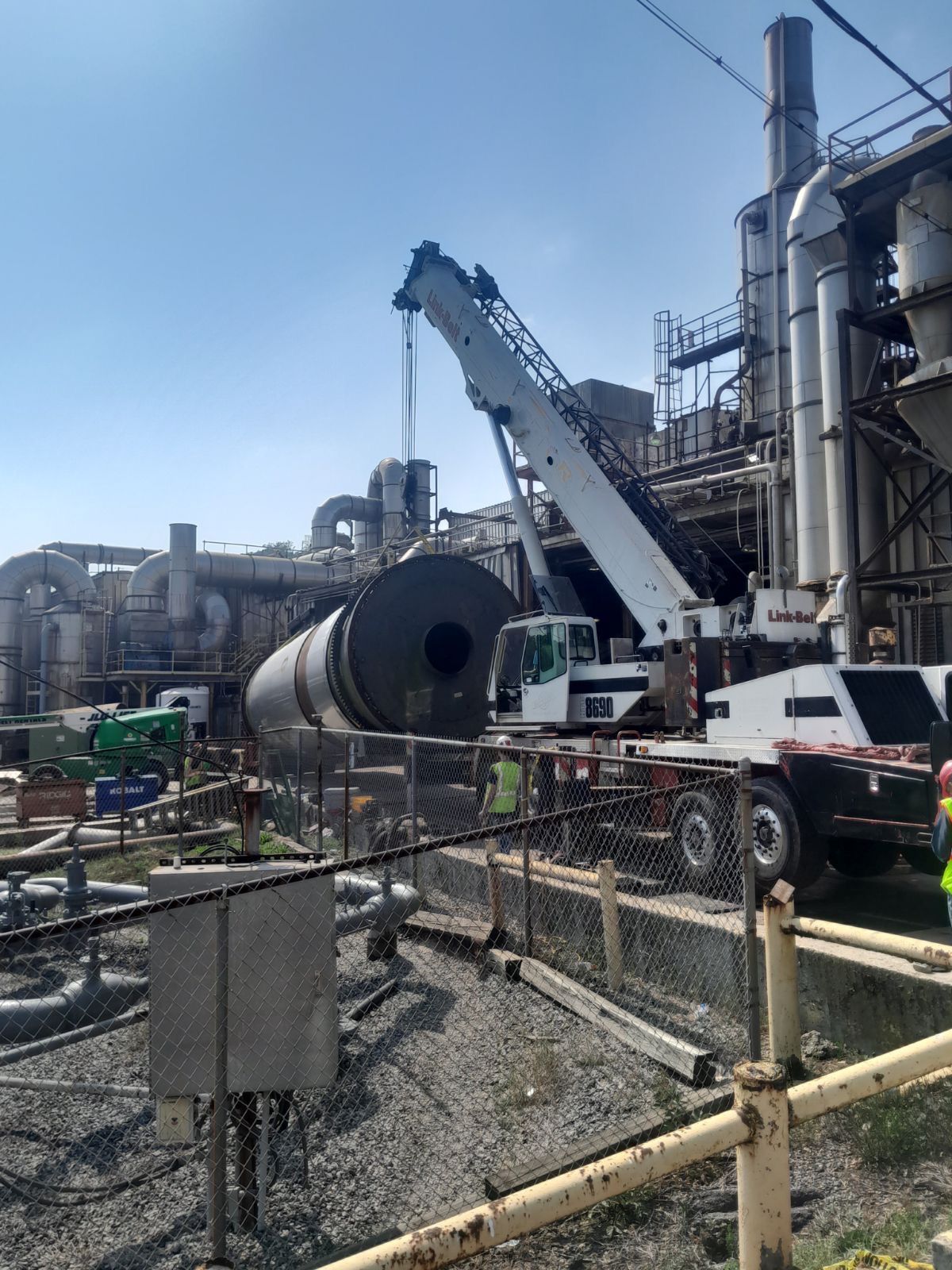 A crane is lifting a large object in front of a factory.