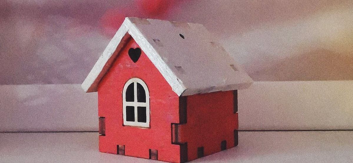 A small red house with a heart on the roof is sitting on a table.