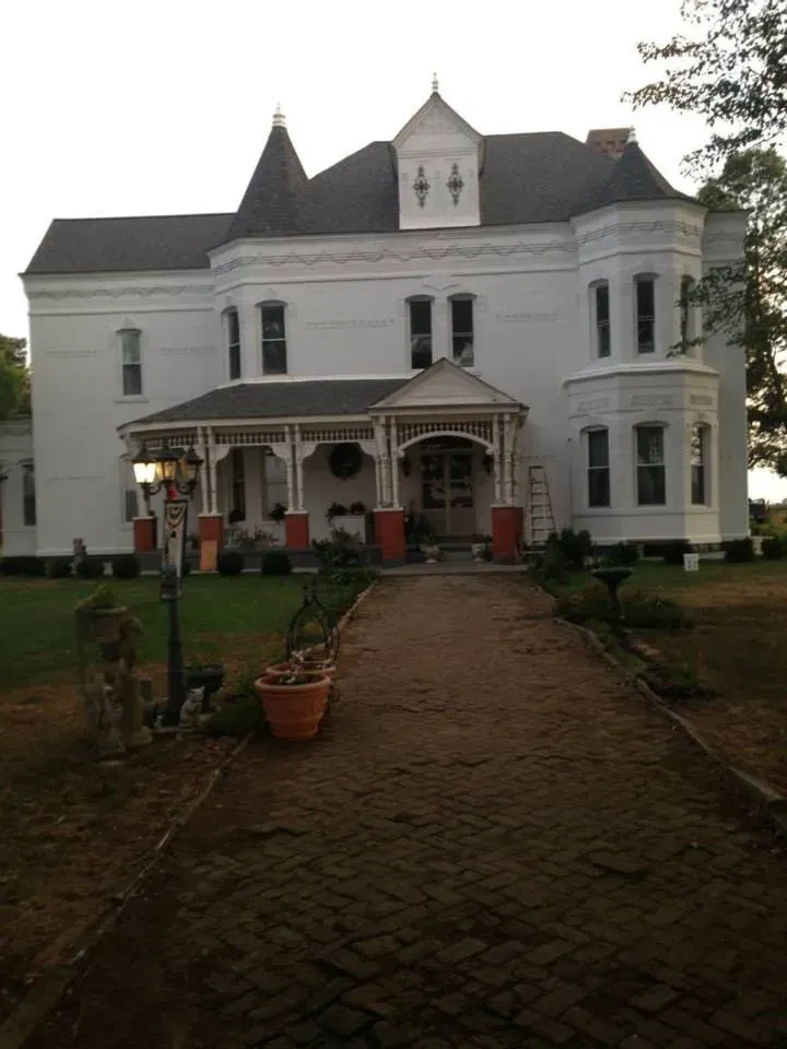 A large white house with a brick walkway leading to it