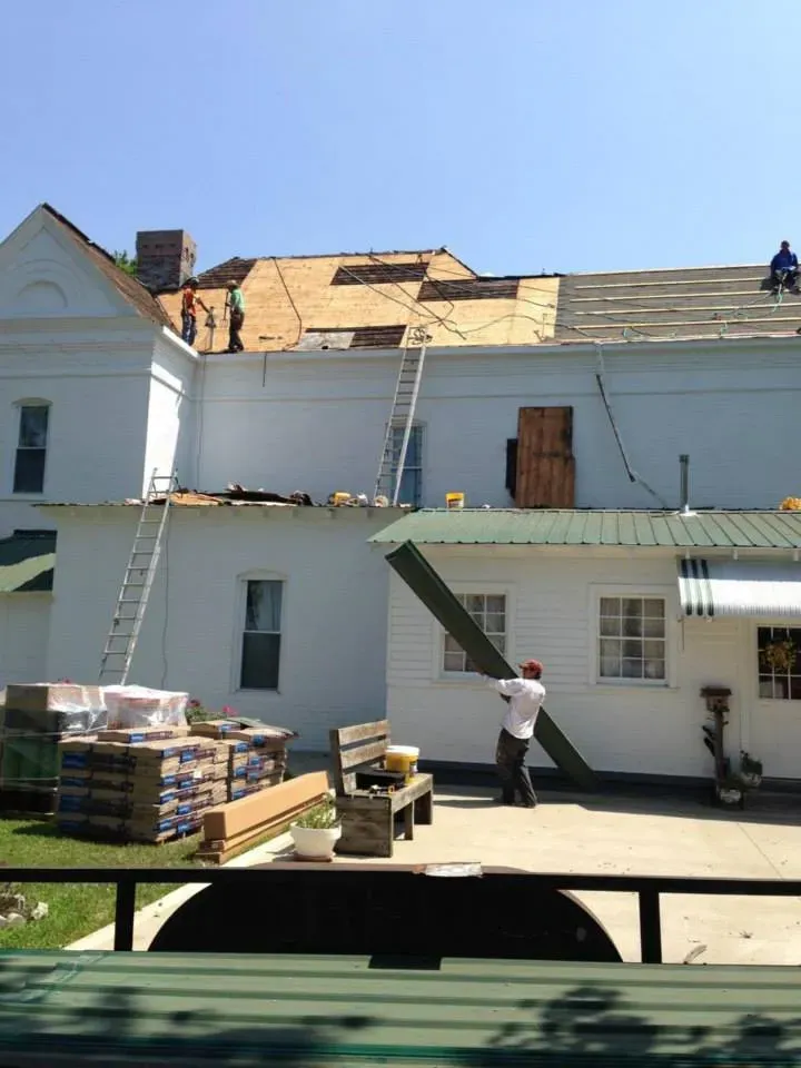 A man is working on the roof of a white house