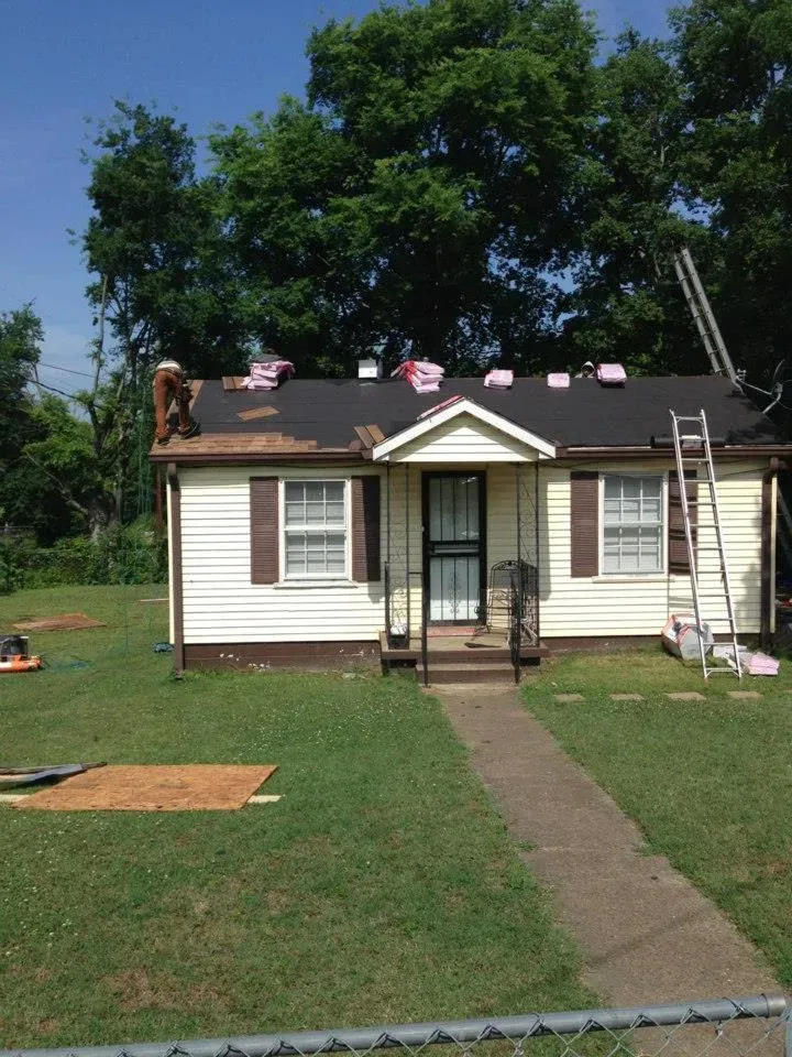 A white house with a black roof is being remodeled