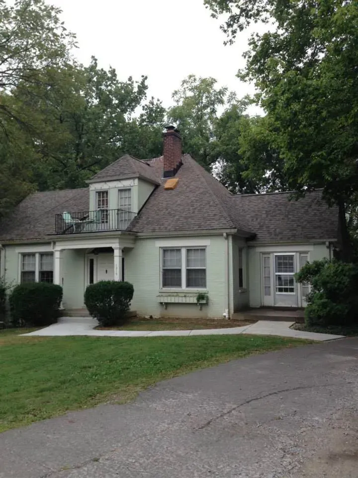 A white house with a gray roof and a balcony