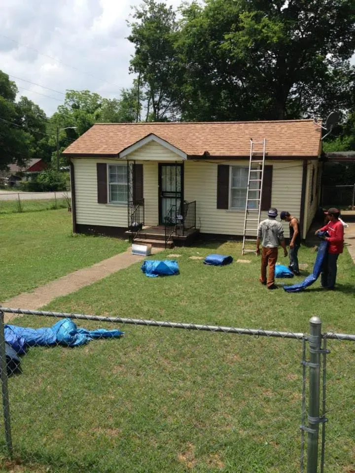 A group of people are working on the roof of a house