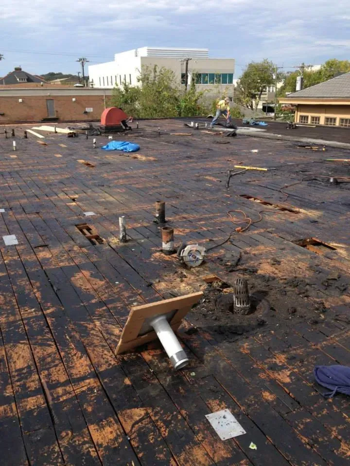 A roof with a lot of holes in it and a building in the background.