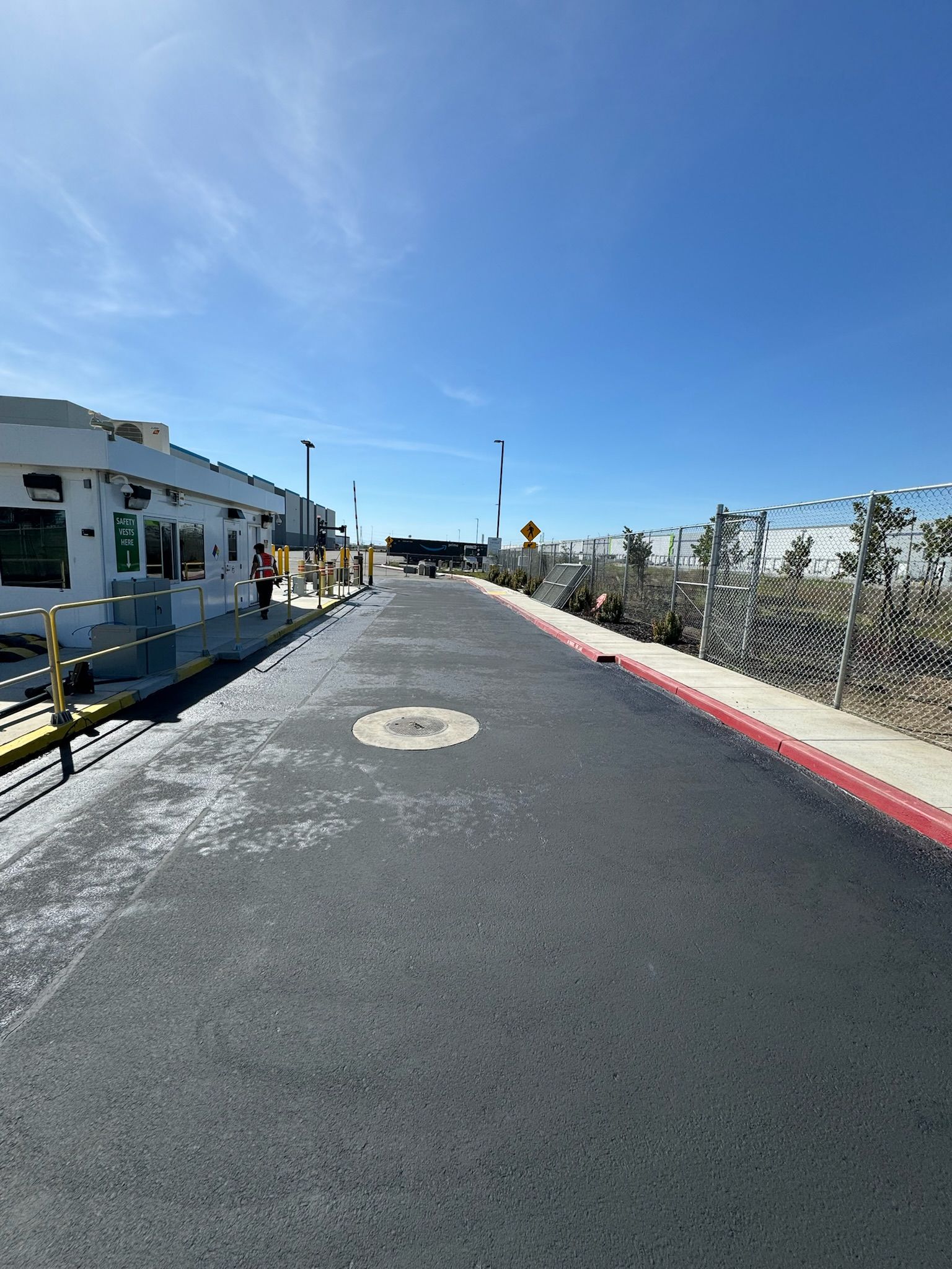 A road with a fence and a building on the side of it.