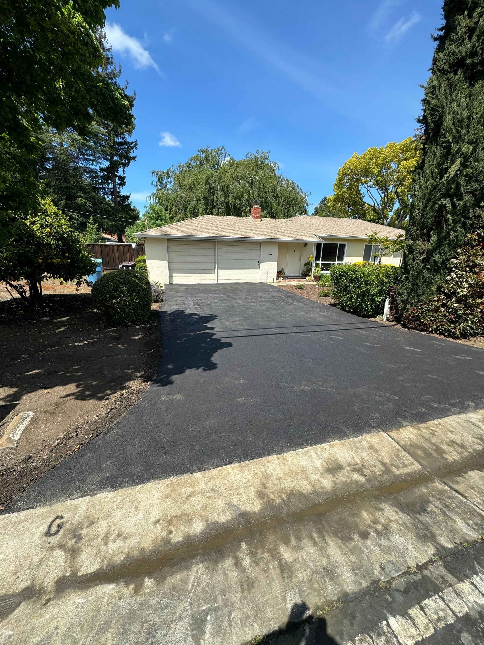 A driveway leading to a house with trees in the background