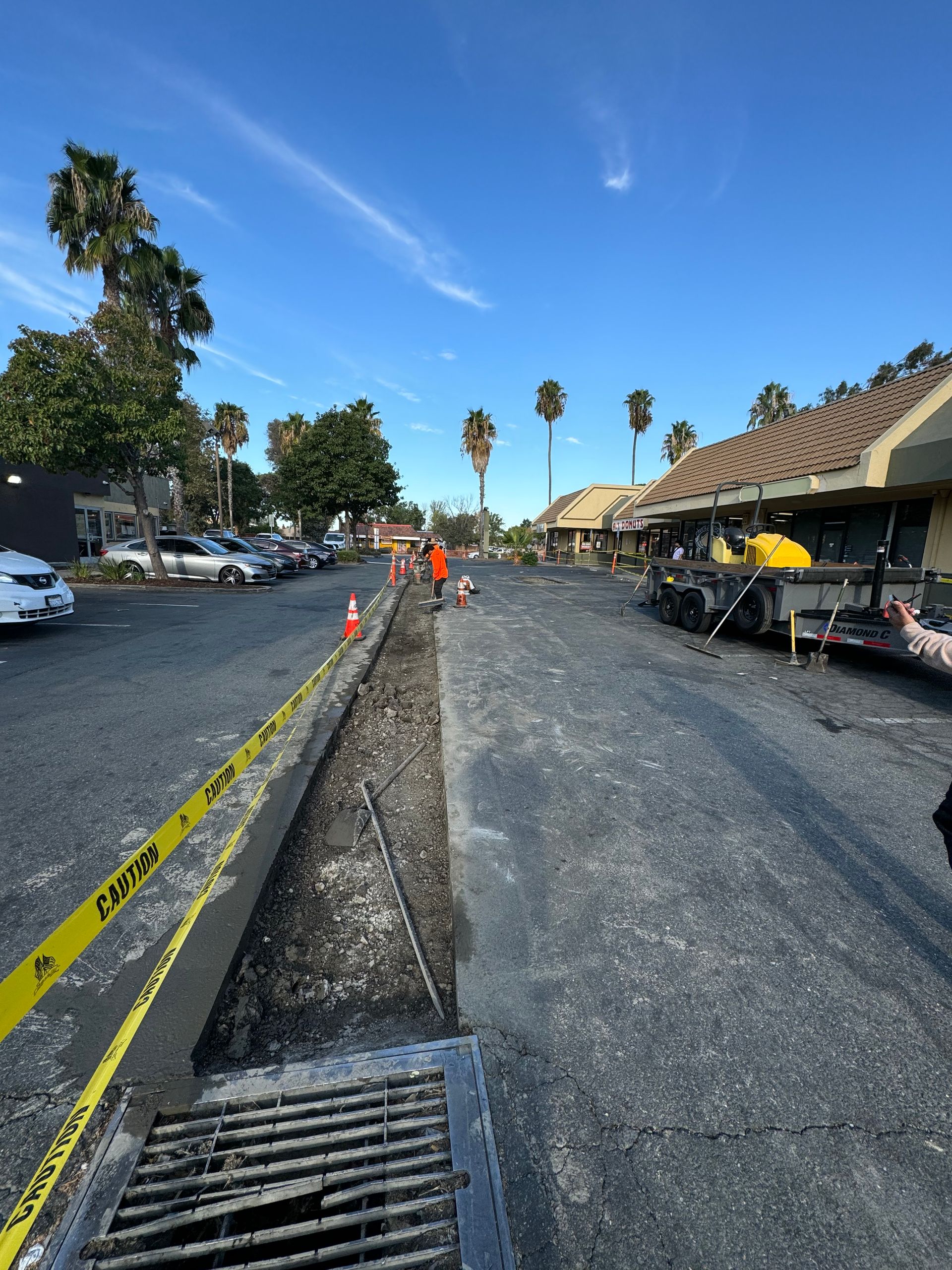 A drain in a parking lot with a yellow caution tape around it