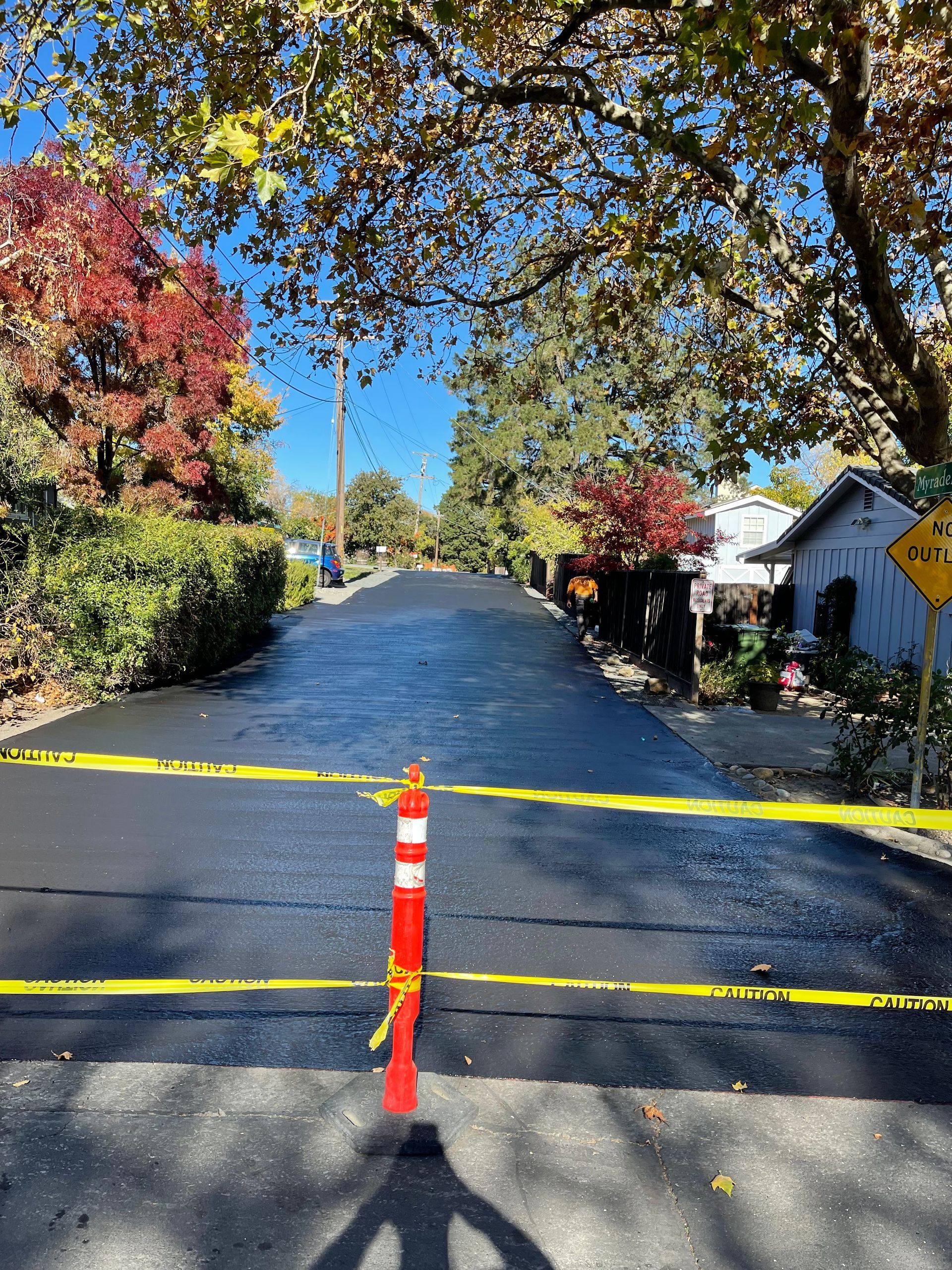 A road with a yellow tape covering it and a red pole in the middle.