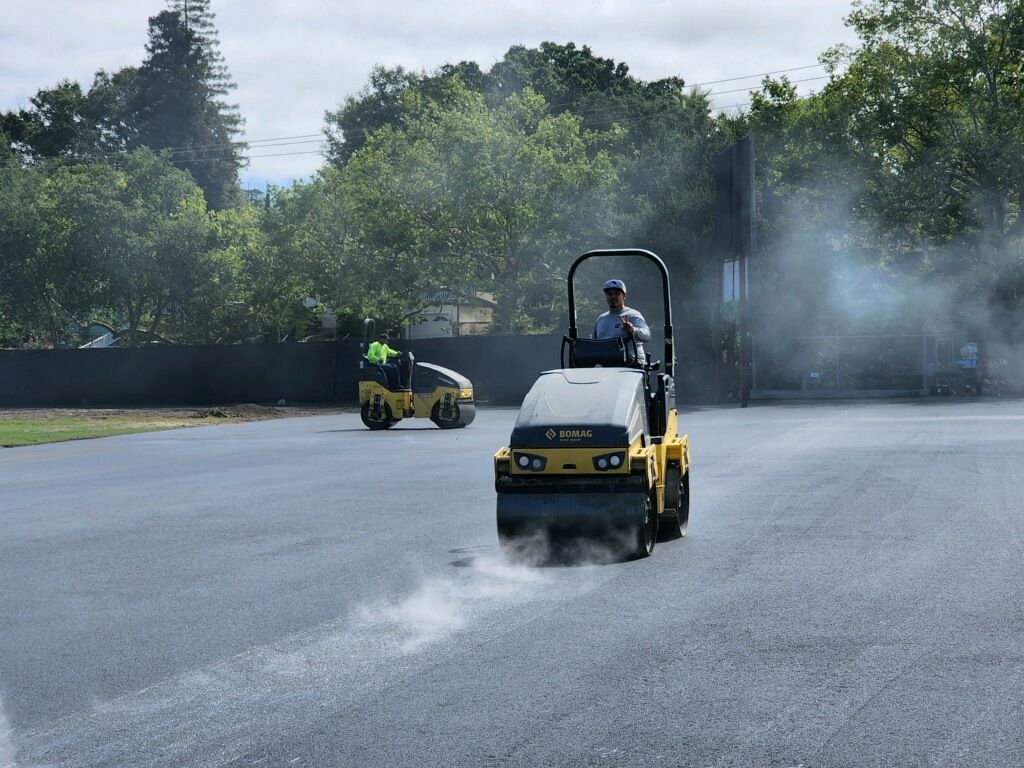 A man is driving a yellow roller on a road