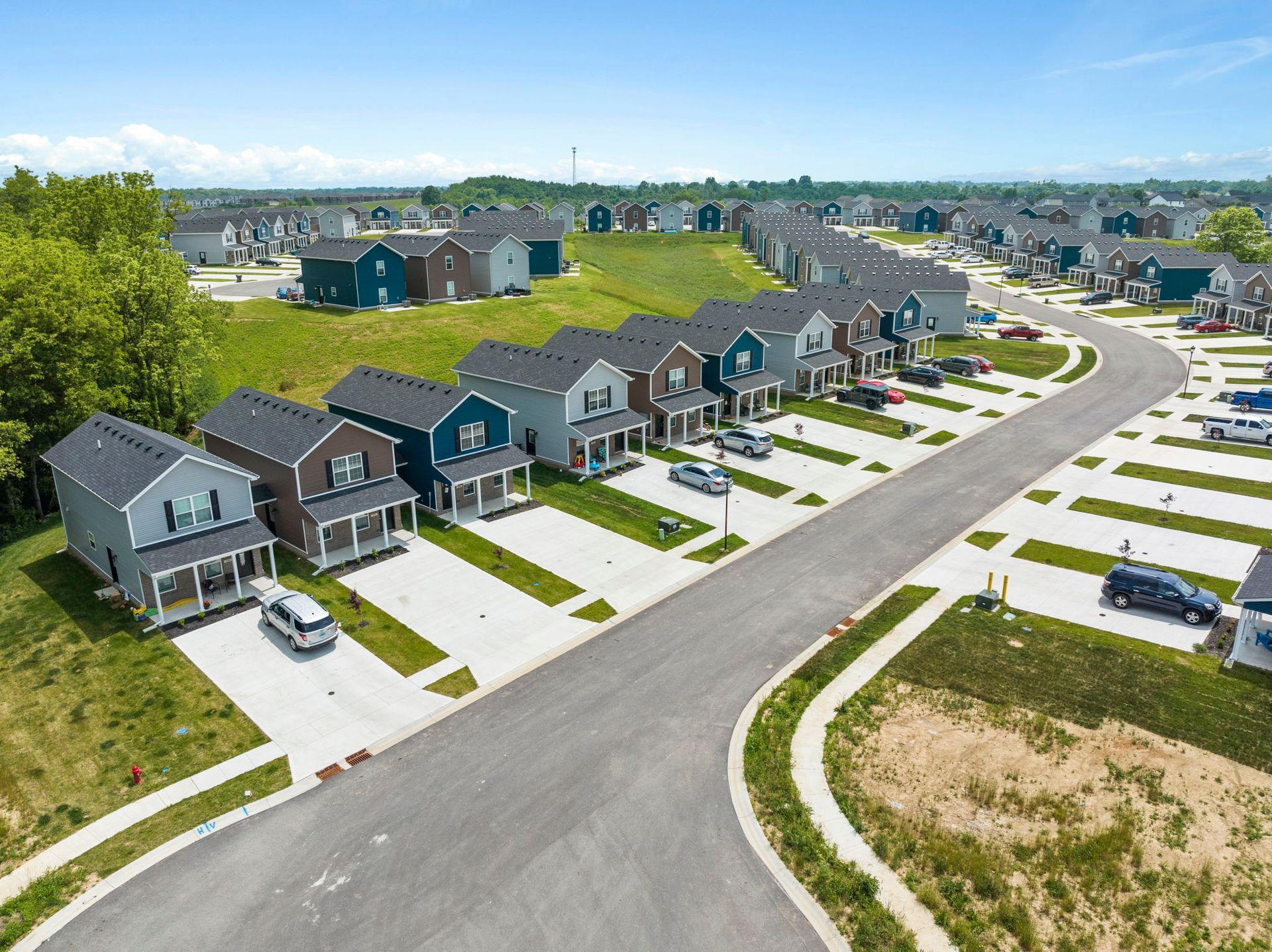 An aerial view of a residential neighborhood with lots of houses and cars parked on the side of the road.