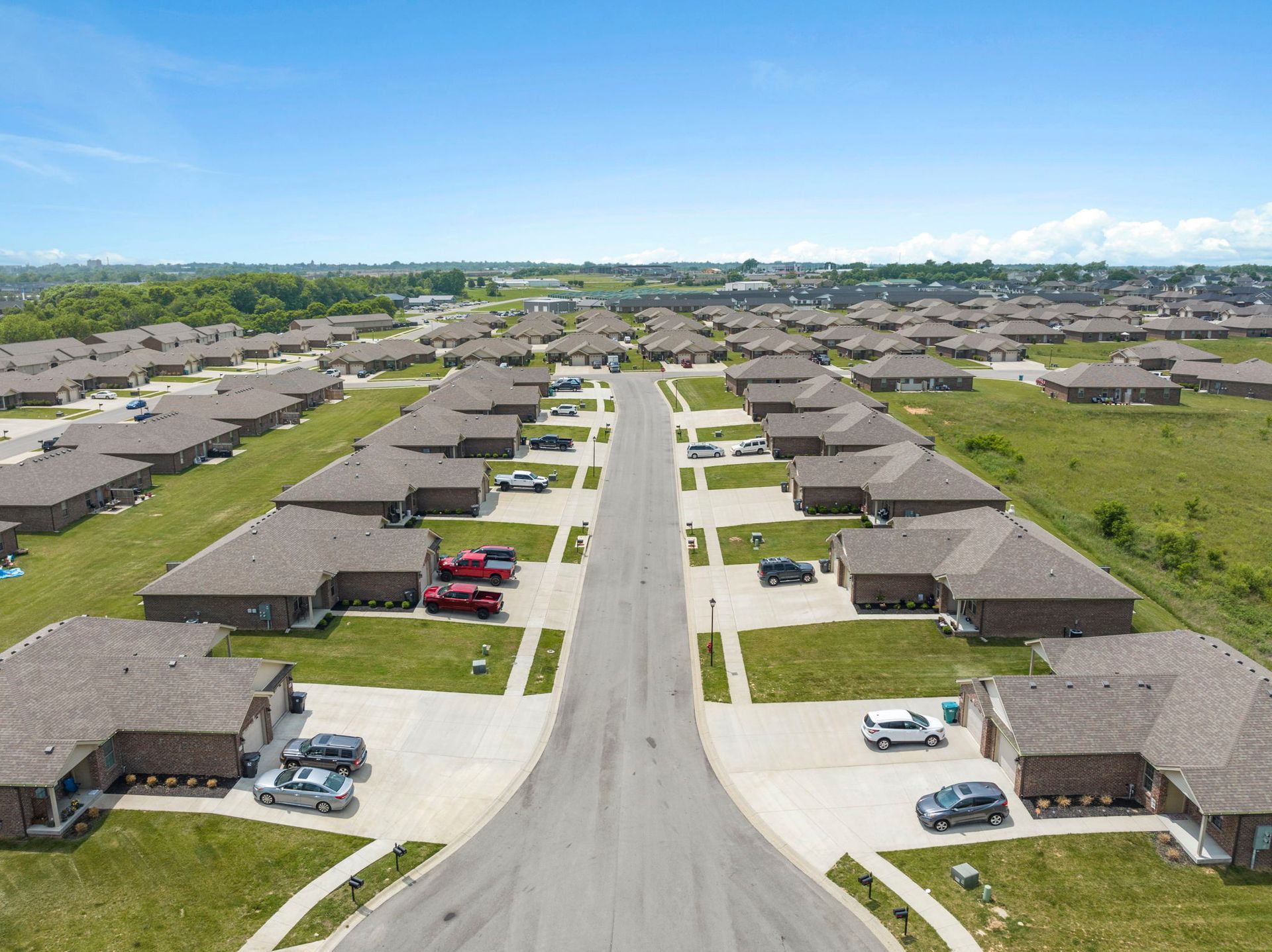 An aerial view of a residential neighborhood with lots of houses and cars parked on the side of the road.