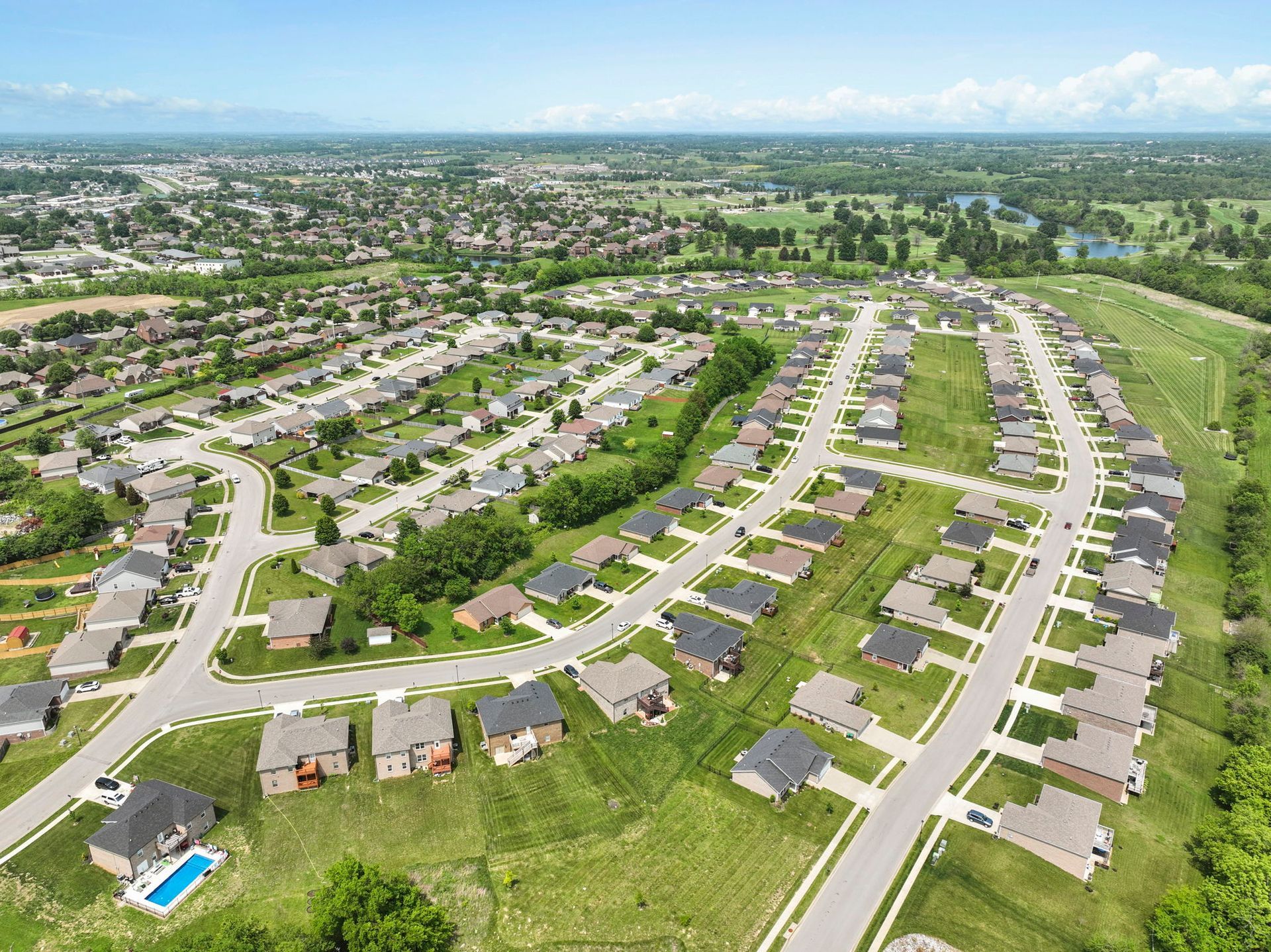 An aerial view of a residential neighborhood with lots of houses and a pool.