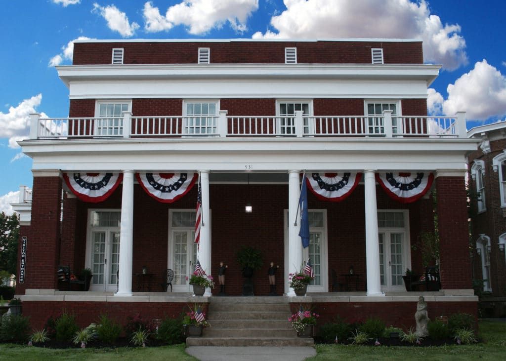 A large red brick house with white columns and a balcony