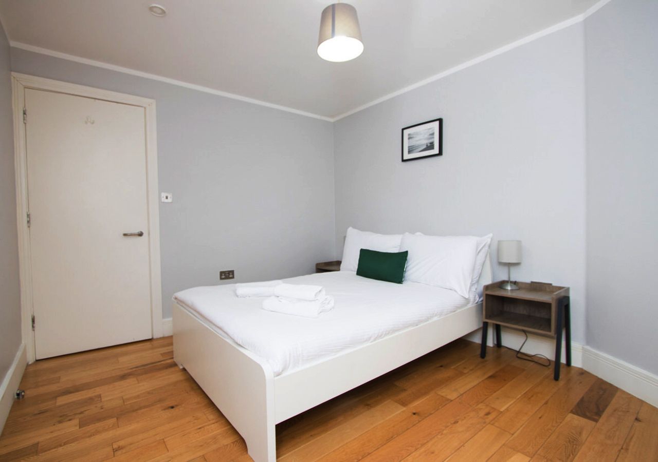 A bedroom with a white bed and wooden floors