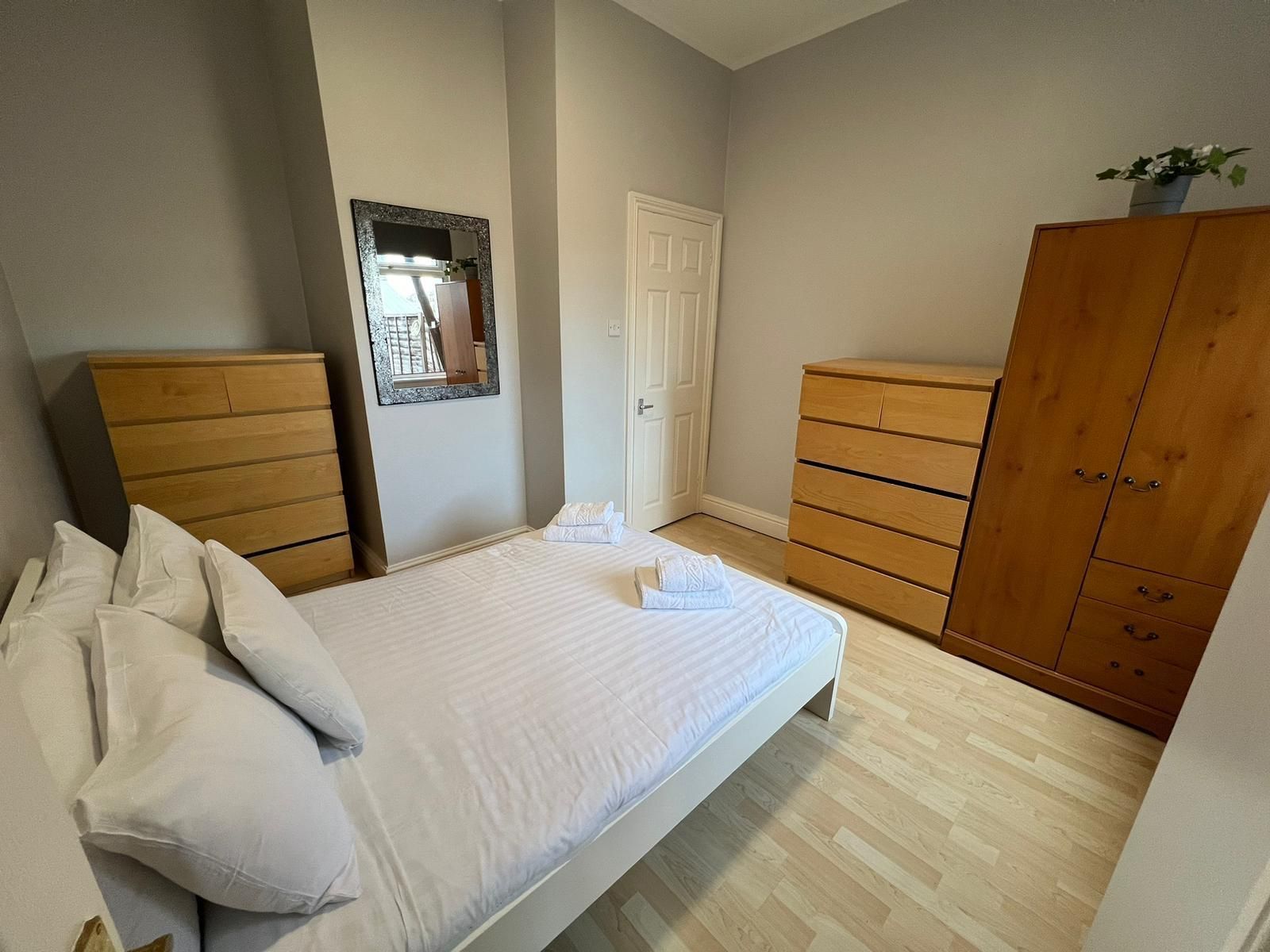A bedroom with a bed , dresser , and mirror.