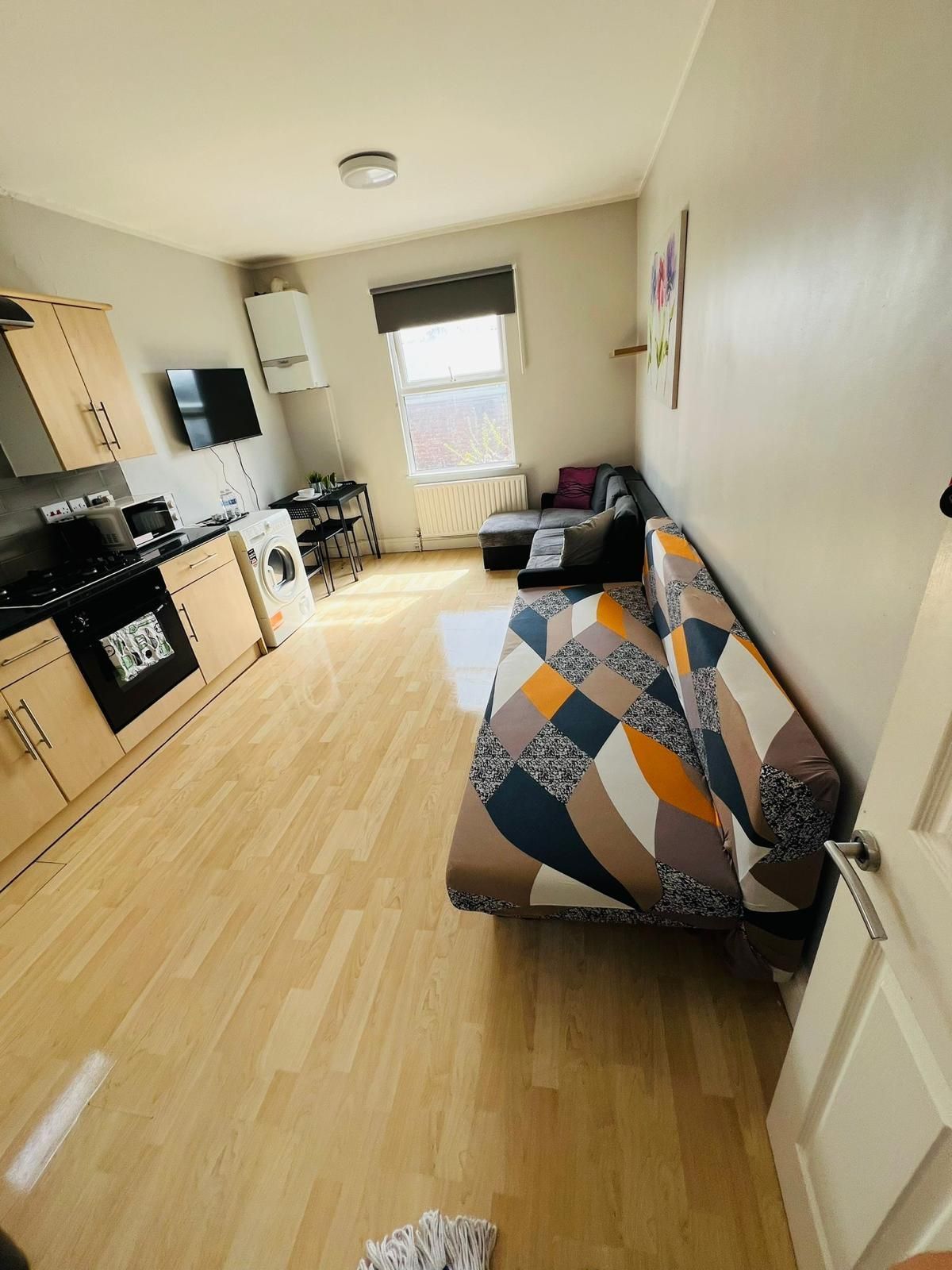 A living room with a couch and a kitchen in the background