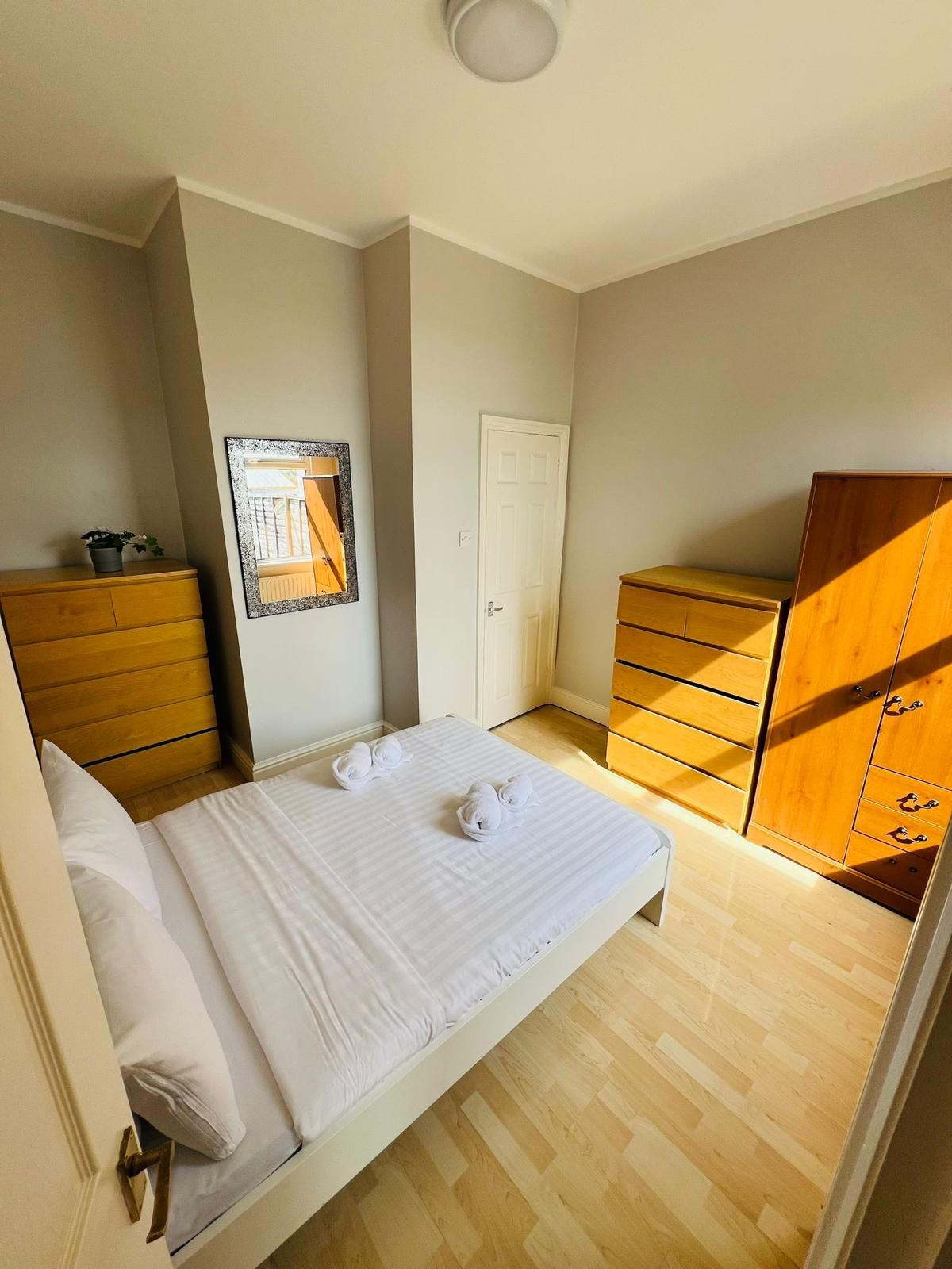 A bedroom with a bed , dressers , and a mirror.