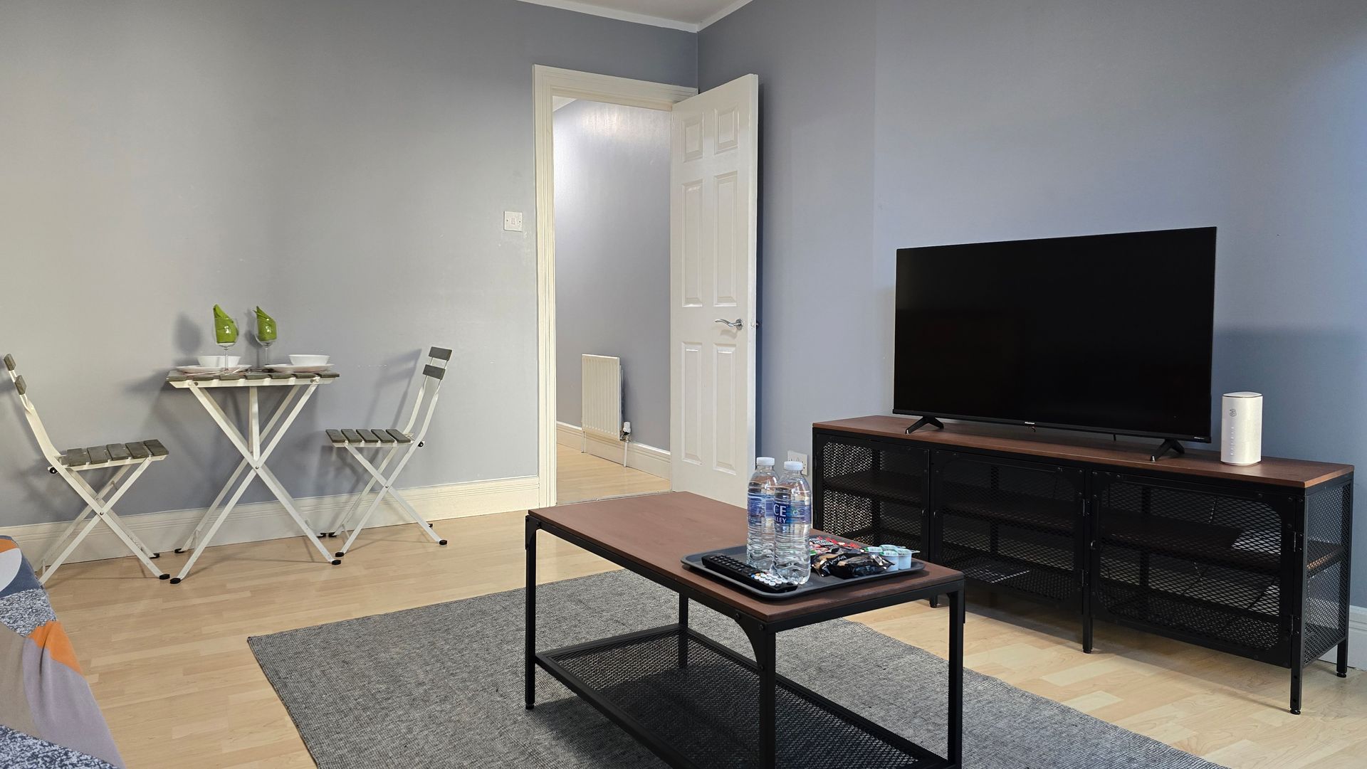 A living room with a table , chairs , and a flat screen tv.