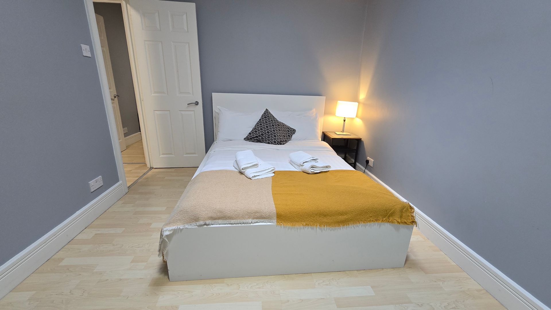 A bedroom with a bed , nightstand and lamp.