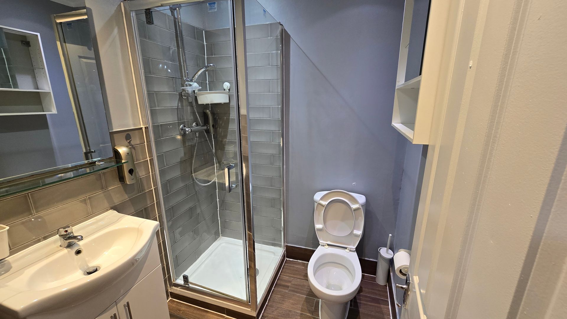 A bathroom with a toilet , sink , shower and mirror.
