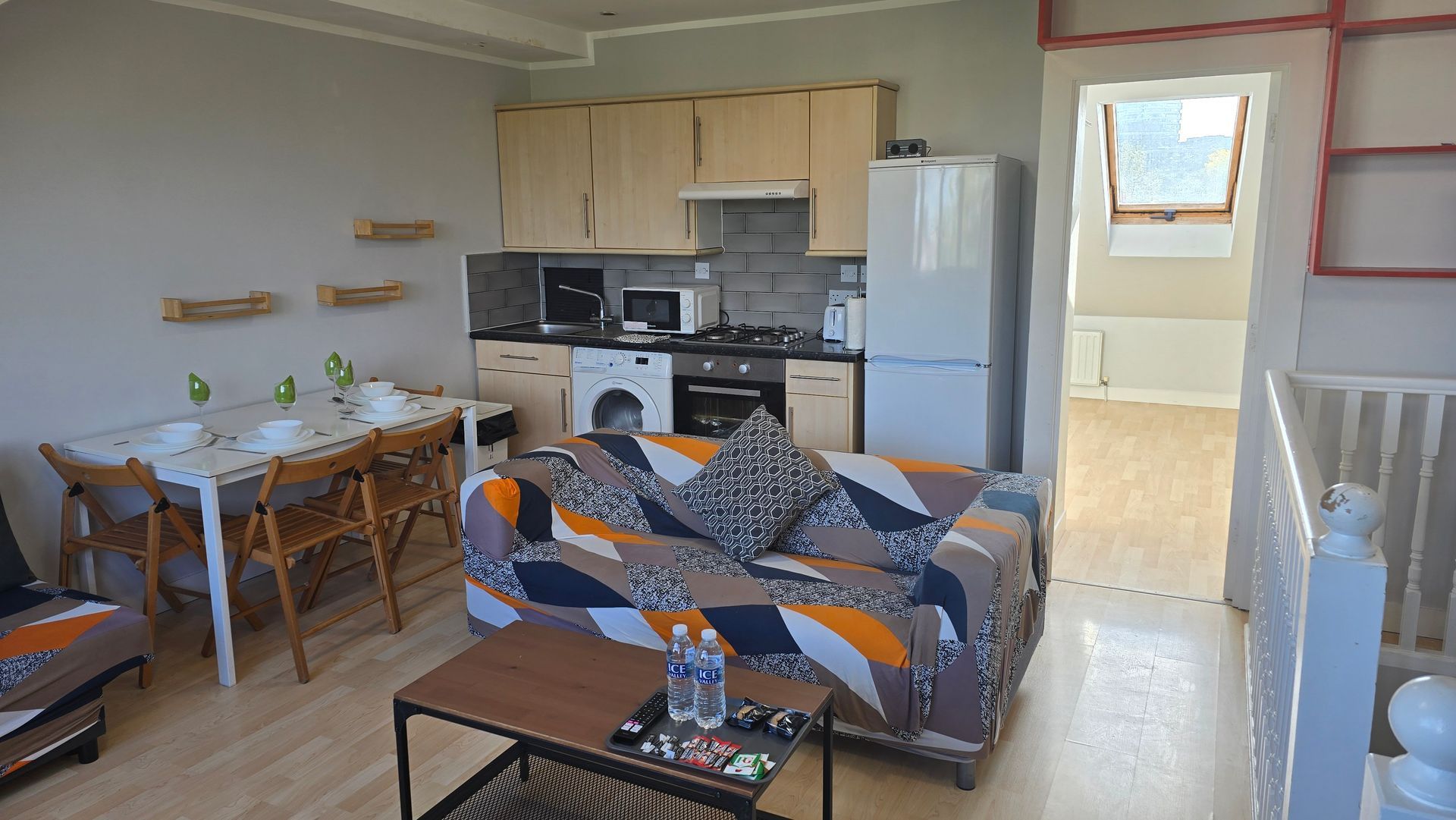 A living room with a couch a table and a refrigerator