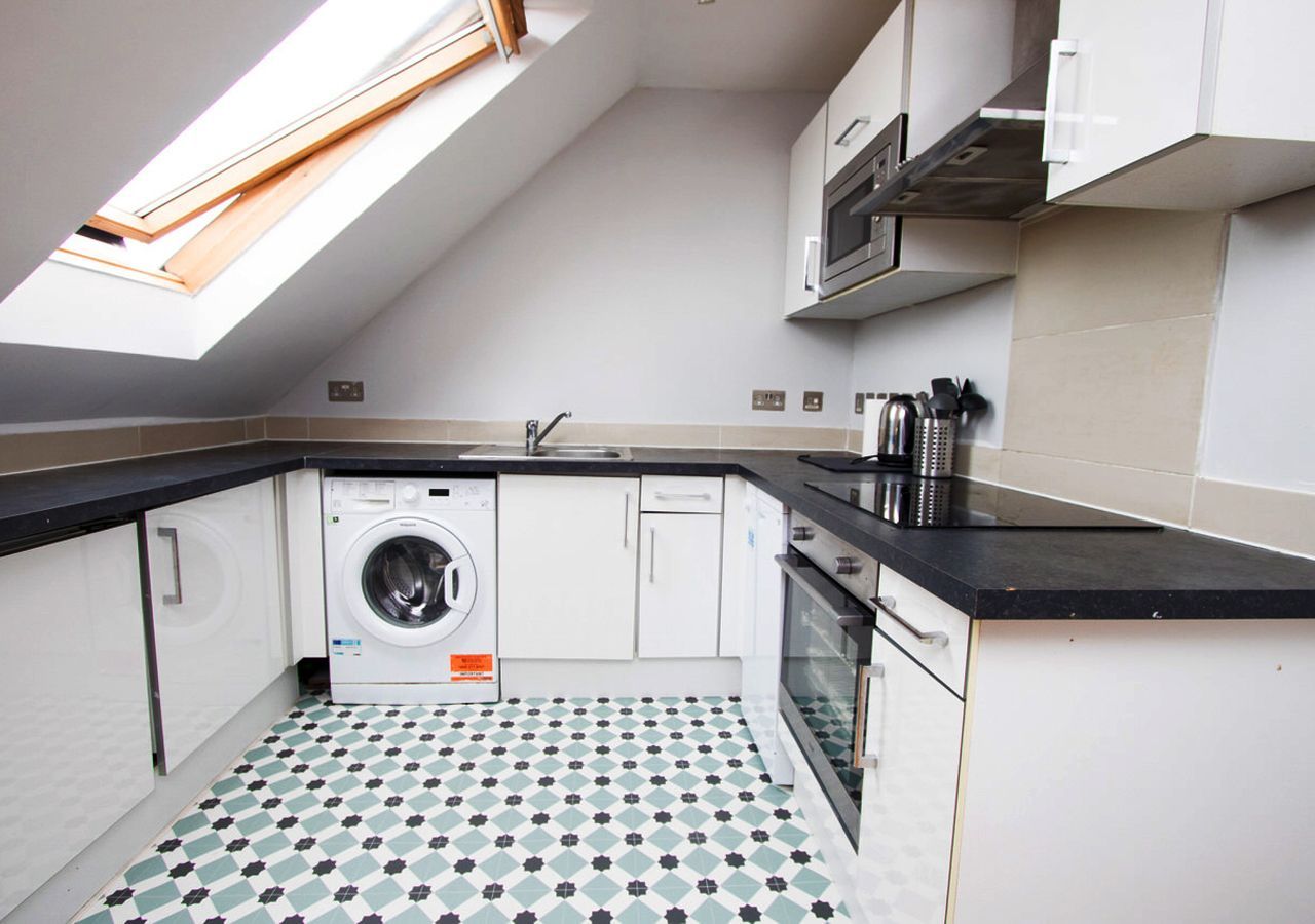 A kitchen with a washer and dryer and a skylight
