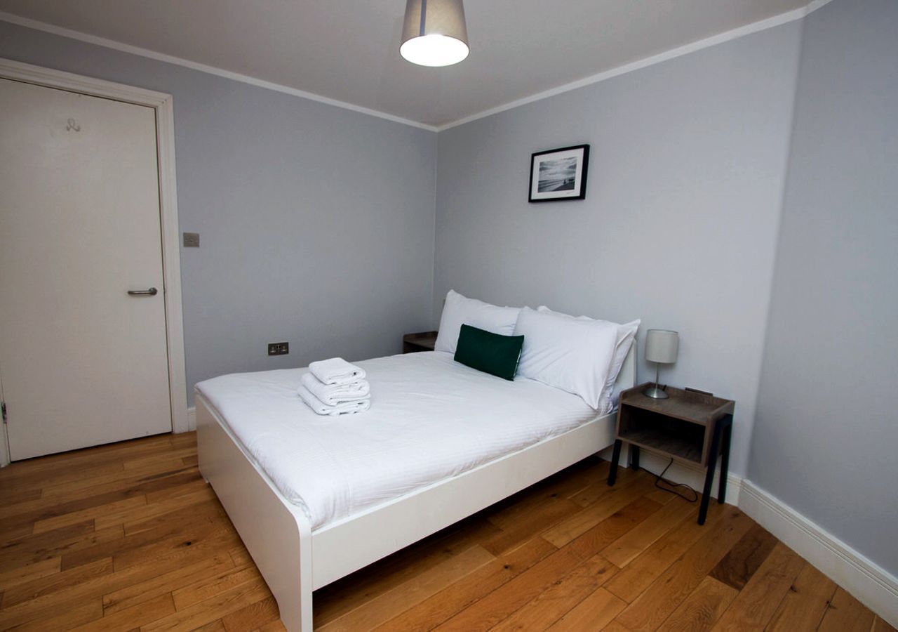 A bedroom with a bed , nightstand , and lamp.