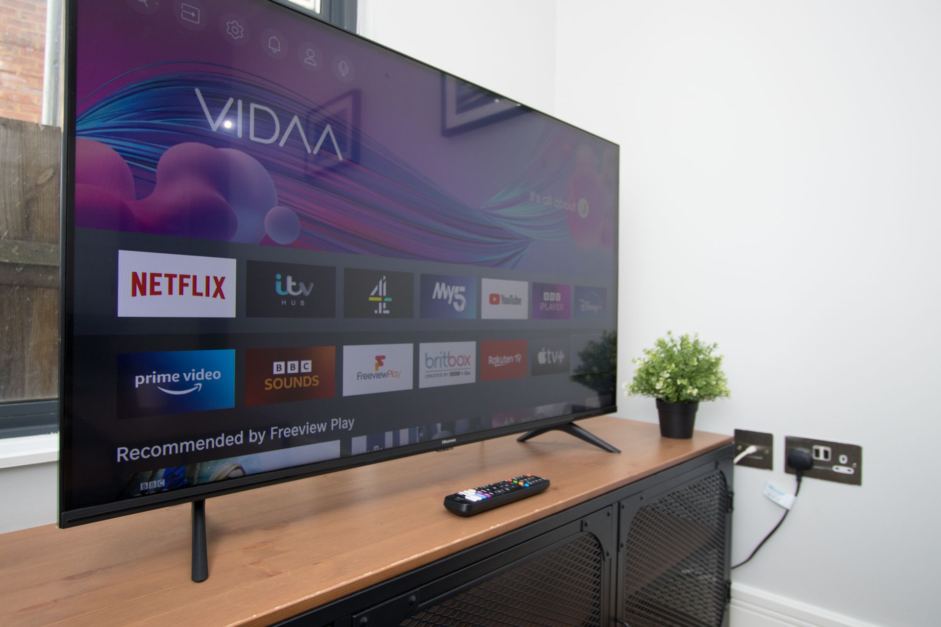 A flat screen tv is sitting on a wooden shelf next to a remote control.