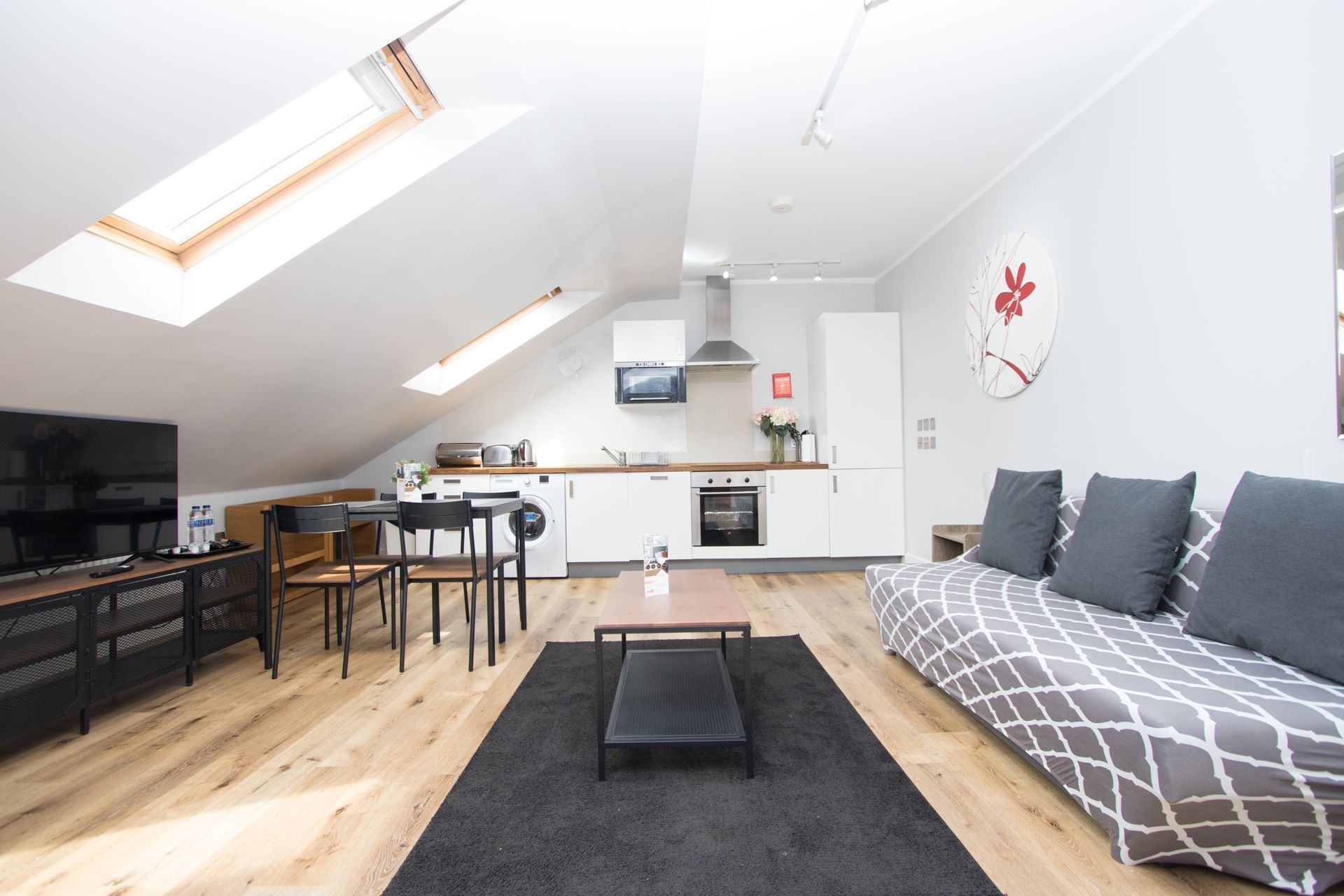 A living room with a couch , table , chairs and a flat screen tv.