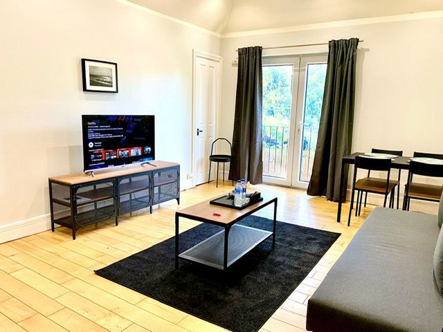 A living room with a couch , table , chairs and a flat screen tv.