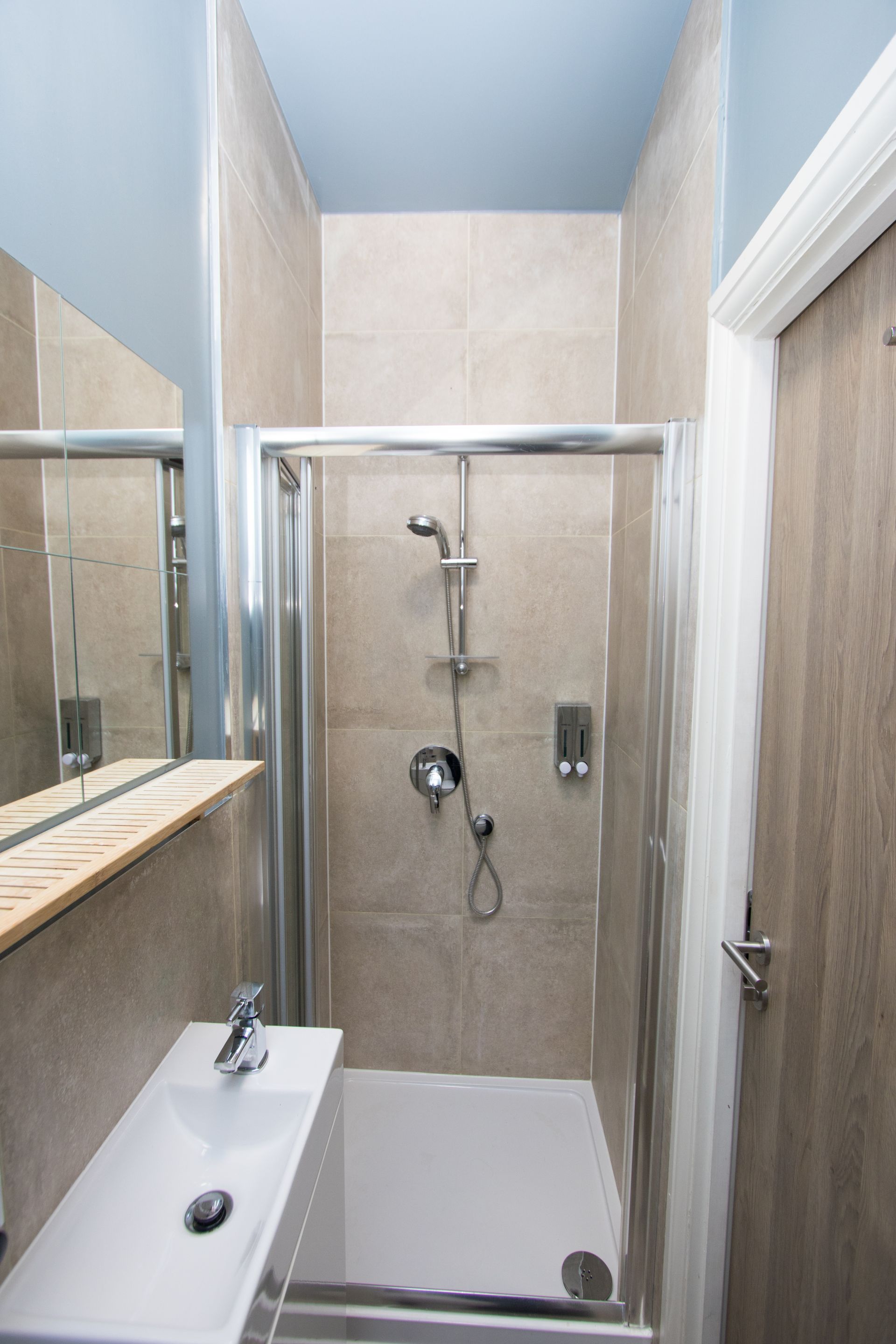 A bathroom with a shower , sink and mirror.