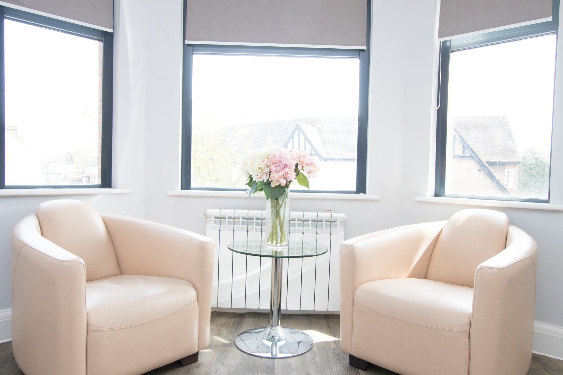 A living room with two chairs and a table with a vase of flowers on it.