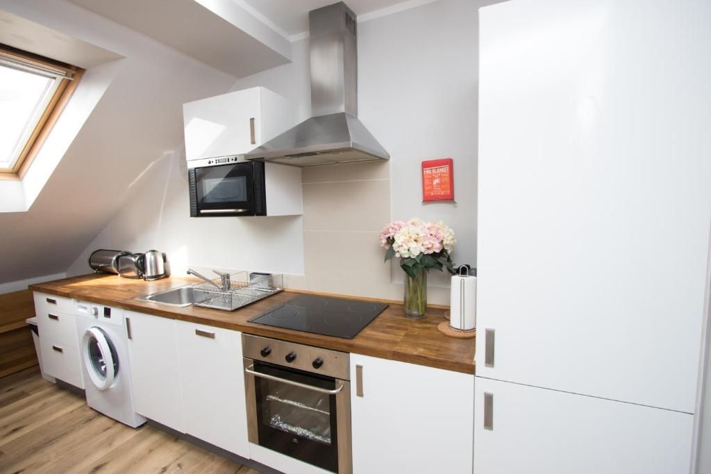 A kitchen with white cabinets , a stove , a refrigerator , a washer and dryer , and a window