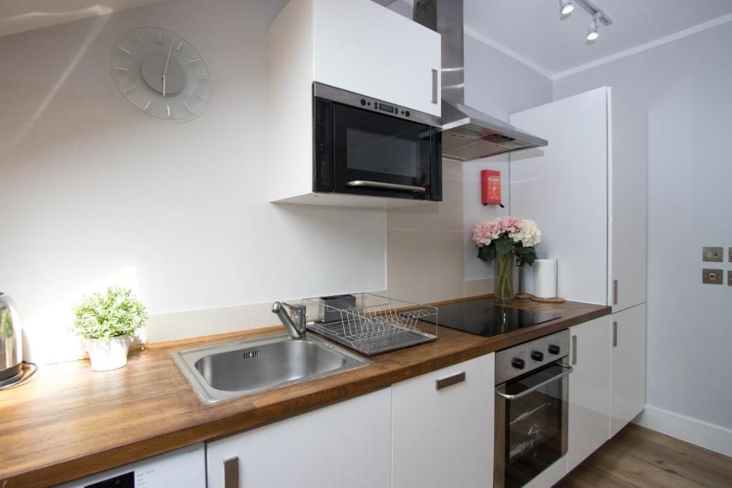 A kitchen with white cabinets , a sink , a stove , and a microwave.