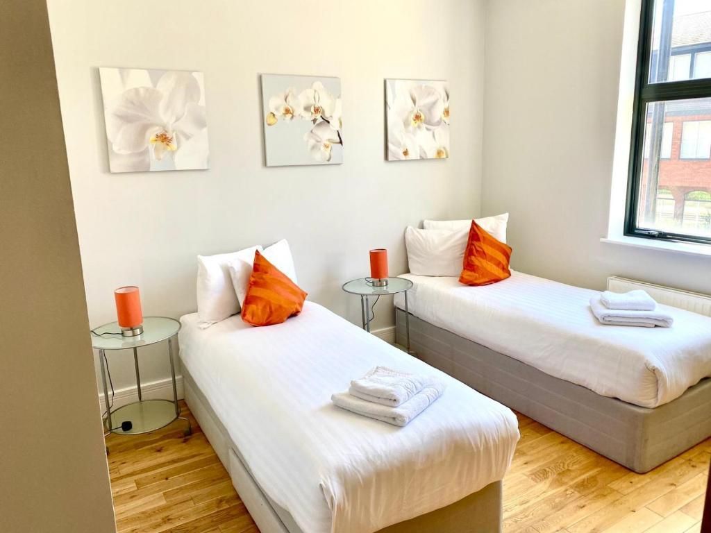 A bedroom with two twin beds and two lamps.