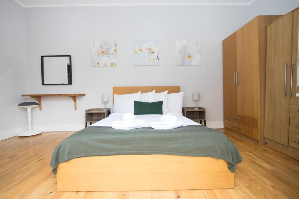 A bedroom with a large bed and a wooden floor