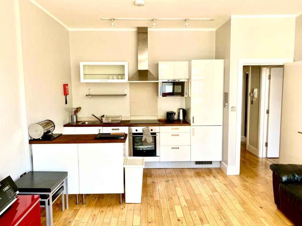 A kitchen with white cabinets and wooden floors