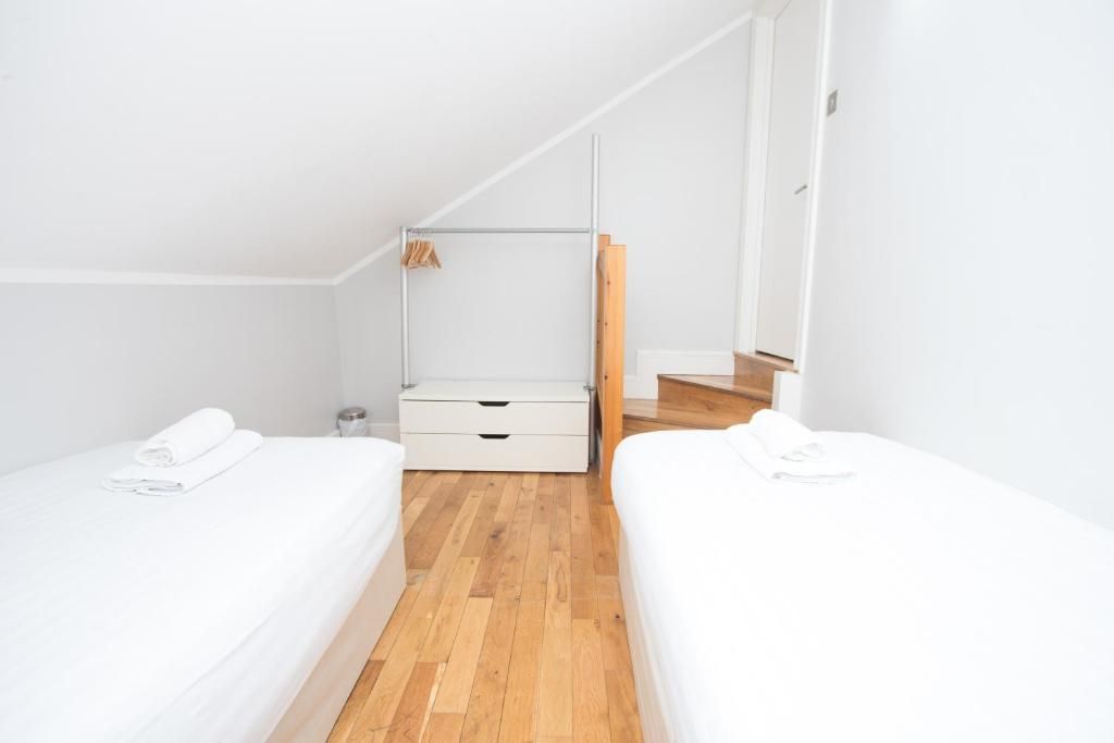 A bedroom with two beds and a wooden floor.
