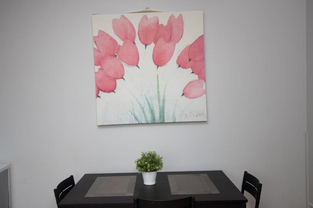 A painting of pink flowers hangs above a dining table