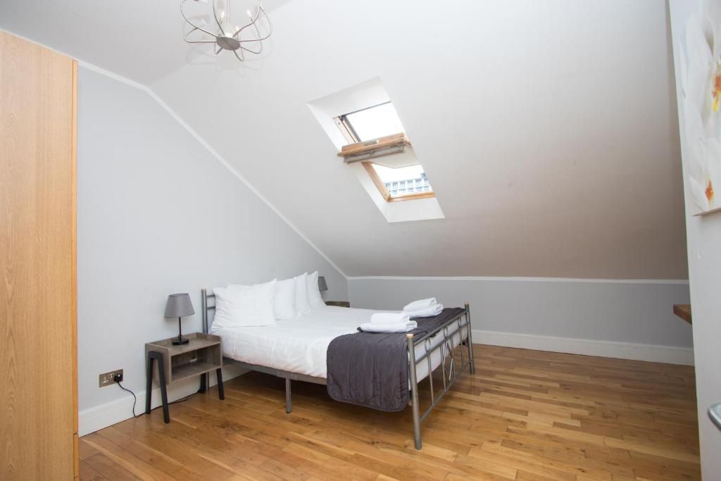 A bedroom with a bed and a skylight in the ceiling.