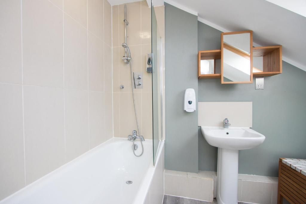 A bathroom with a bathtub , sink , and shower.