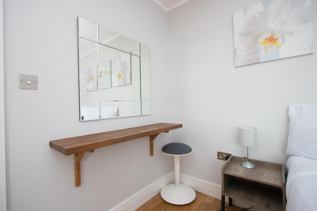 A bedroom with a large mirror and a stool.