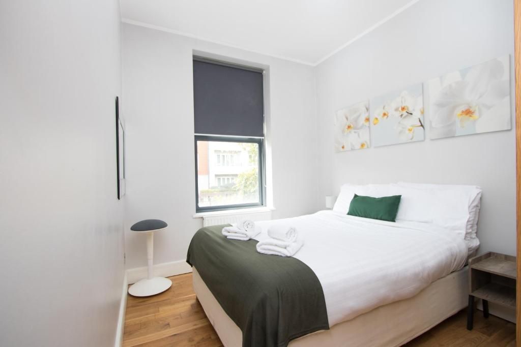 A bedroom with a bed , a window , and a stool.