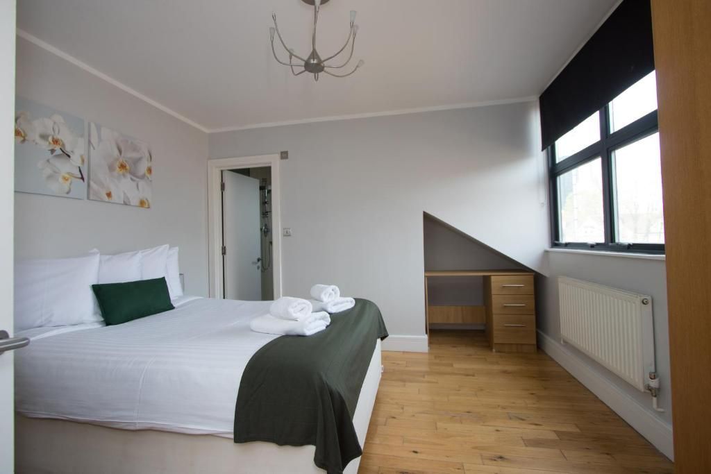 A bedroom with a king size bed , a desk , and a window.