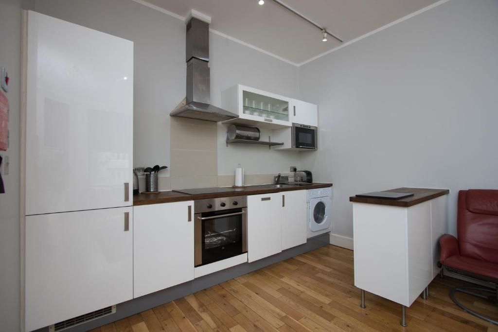 A kitchen with white cabinets and wooden floors