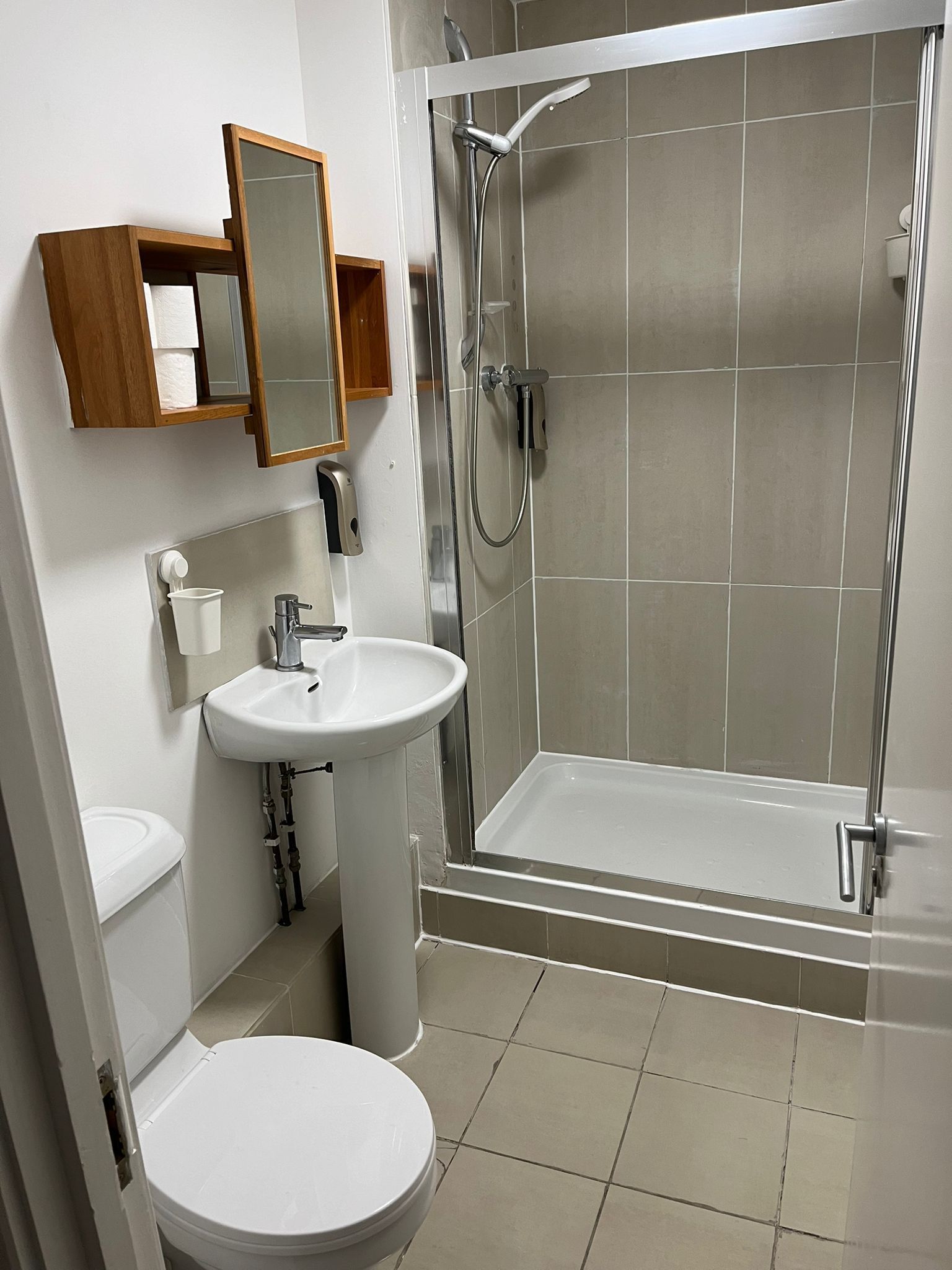 A bathroom with a toilet , sink and shower.