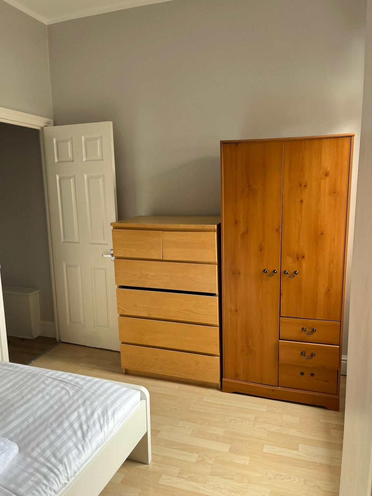 A bedroom with a bed , dresser , and wardrobe.
