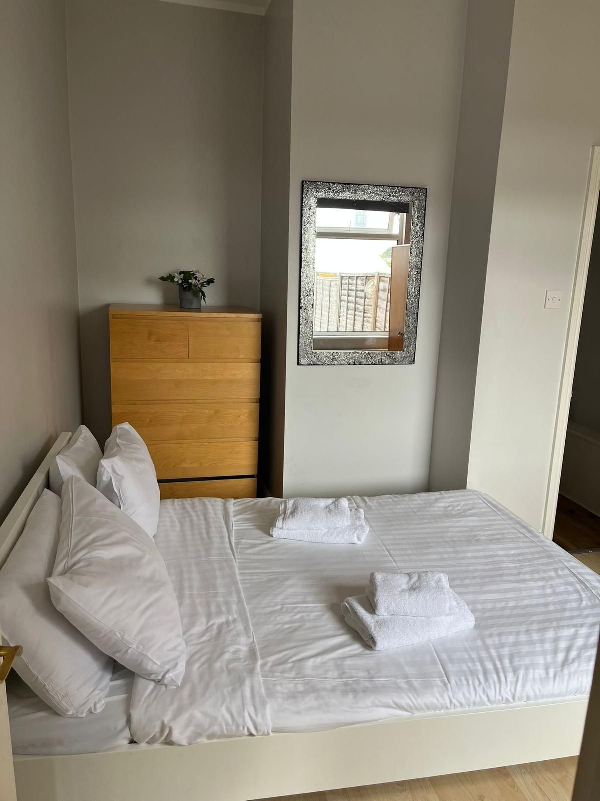 A bedroom with a bed , dresser and mirror.
